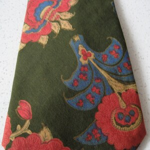 May include: A green silk tie with a floral pattern in shades of red, blue, and gold. The flowers are stylized and have a paisley-like design.