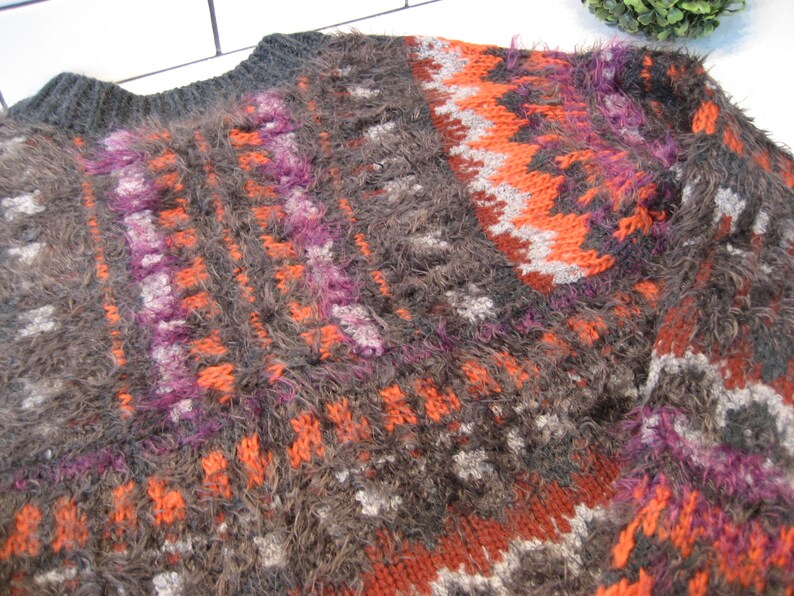 May include: A brown, orange, purple, and gray fuzzy knit sweater with a geometric pattern.