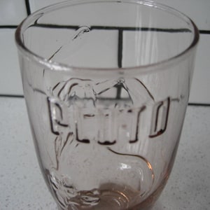 May include: A clear glass drinking glass with the word "ETRO" embossed on the side.