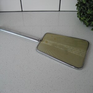 May include: A vintage hand mirror with a silver handle and a rectangular, green-tinted glass mirror with a decorative pattern.