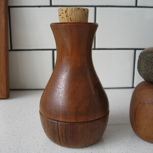 K&ouml;nnte beinhalten: Ein Flaschenverschluss aus Holz mit einem Korken. Der Flaschenverschluss ist aus dunklem Holz und hat eine abgerundete Form.
