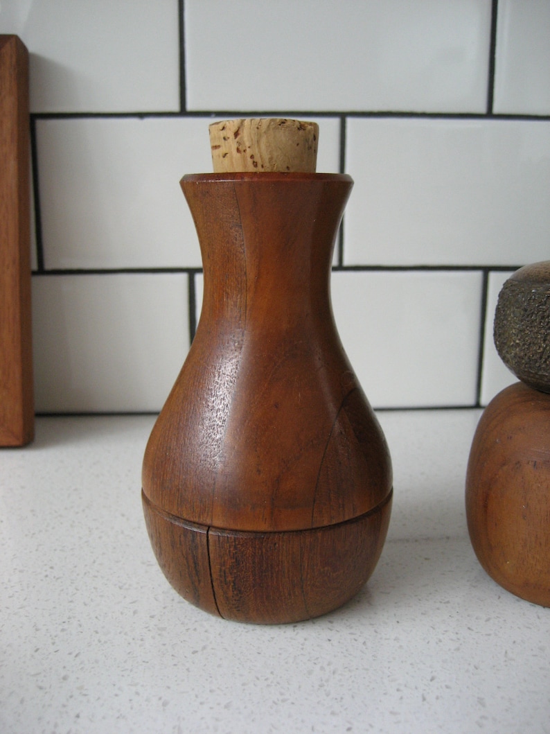 K&ouml;nnte beinhalten: Ein Flaschenverschluss aus Holz mit einem Korken. Der Flaschenverschluss ist aus dunklem Holz und hat eine abgerundete Form.