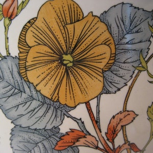 May include: A vintage ceramic plate with a floral design featuring a large yellow flower with orange accents and gray leaves.
