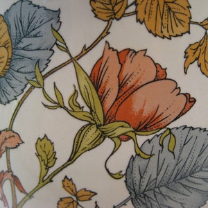 May include: A vintage ceramic pitcher with a floral design featuring a large pink rose, yellow flowers, and green leaves on a white background.