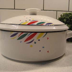 Puede incluir: Plato para hornear de cerámica blanca con tapa. El plato tiene un diseño abstracto colorido con acentos rojos, amarillos, verdes y azules.