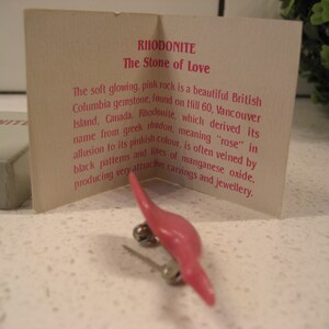 May include: A pink rhodonite stone, also known as the "Stone of Love", is a beautiful British Columbia gemstone. The card describes its origin, name, and unique veining.