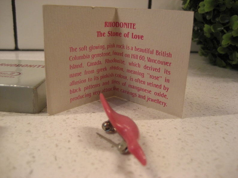 May include: A pink rhodonite stone, also known as the "Stone of Love", is a beautiful British Columbia gemstone. The card describes its origin, name, and unique veining.
