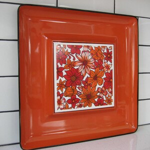 May include: Orange ceramic serving tray with a black border and a floral design in shades of orange, red, and white.