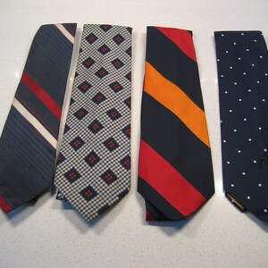 May include: Four neckties in different patterns. The ties are all navy blue with white, red, and orange accents. The patterns include stripes, polka dots, and geometric shapes.