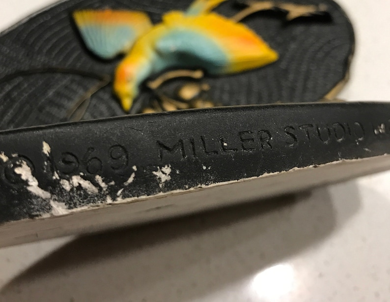 K&ouml;nnte beinhalten: Eine schwarze Keramik-Wandplatte mit einem gelben und blauen Vogelmotiv. Die Platte ist mit 1969 datiert und mit "Miller Studio" signiert.