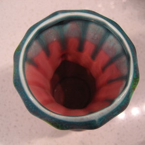 May include: A turquoise and pink glazed ceramic vase with a wide opening and a scalloped rim.