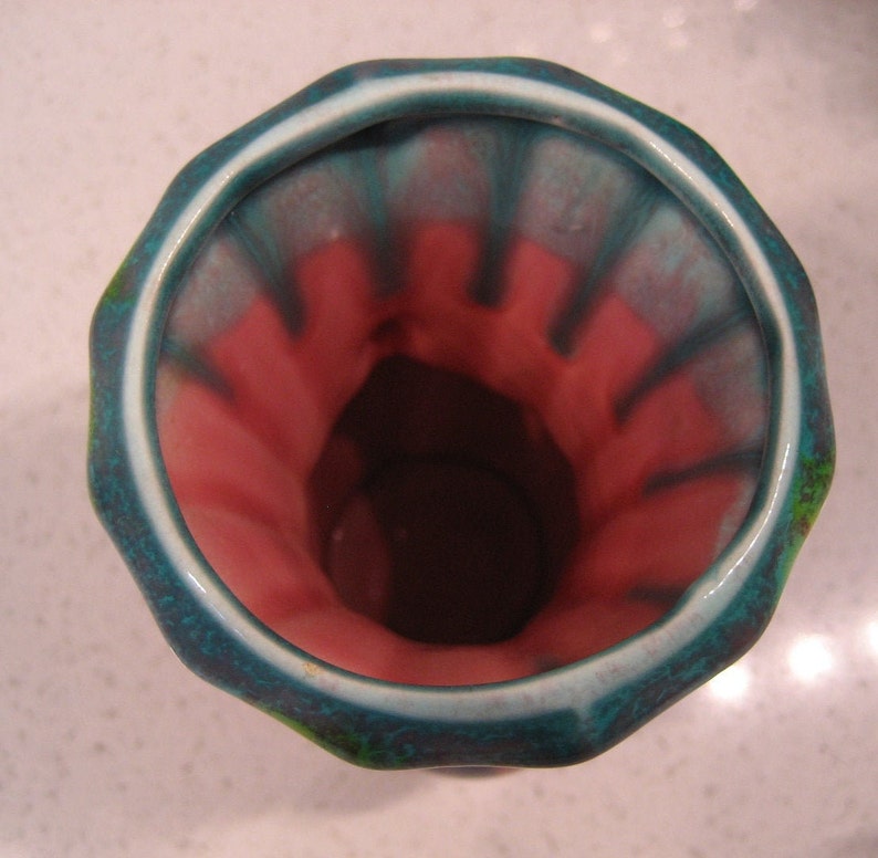 May include: A turquoise and pink glazed ceramic vase with a wide opening and a scalloped rim.