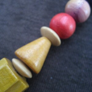May include: A wooden bead necklace with a variety of colors, including red, pink, blue, and yellow. The beads are round and have a smooth finish.