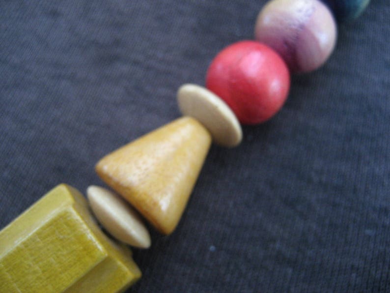 May include: A wooden bead necklace with a variety of colors, including red, pink, blue, and yellow. The beads are round and have a smooth finish.