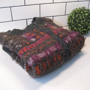 May include: A gray, orange, and purple fuzzy knit cardigan with a plaid pattern.