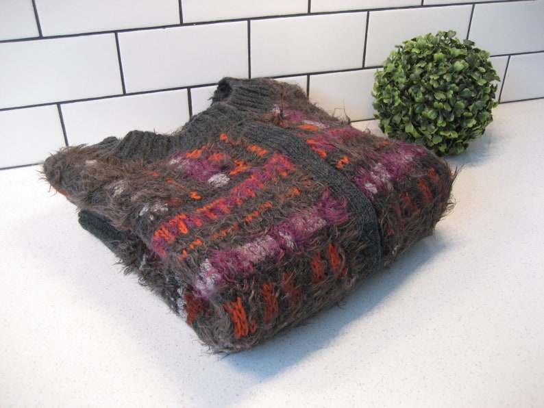 May include: A gray, orange, and purple fuzzy knit cardigan with a plaid pattern.