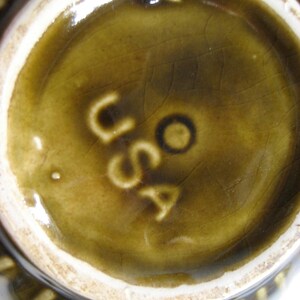 May include: Close-up of the underside of a brown ceramic dish with a white rim. The base of the dish has a brown glaze and the word "USA" is stamped in white.