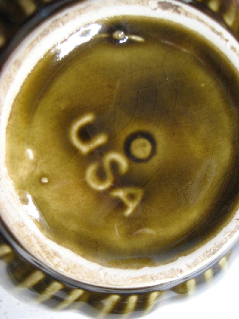 May include: Close-up of the underside of a brown ceramic dish with a white rim. The base of the dish has a brown glaze and the word "USA" is stamped in white.