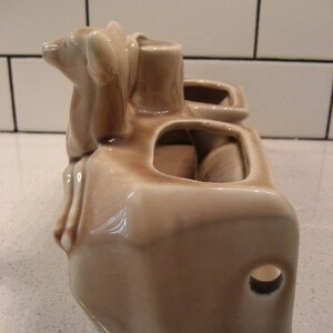 Może przedstawiać: Brązowa ceramiczna doniczka z dwoma figurkami jeleni na g&oacute;rze. Doniczka ma trzy oddzielne przegrody na rośliny.
