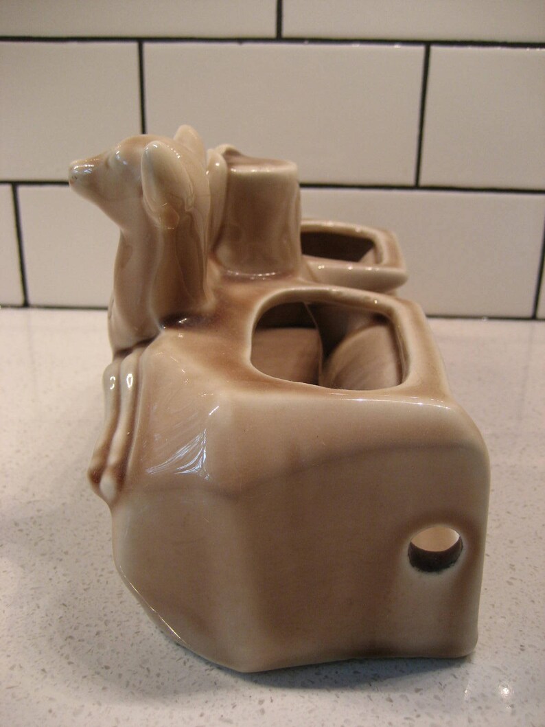 Może przedstawiać: Brązowa ceramiczna doniczka z dwoma figurkami jeleni na g&oacute;rze. Doniczka ma trzy oddzielne przegrody na rośliny.