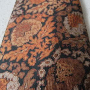 May include: A brown and black patterned tie with a floral design.
