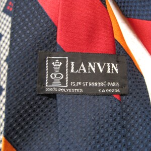 May include: A navy blue, red, white, and orange striped tie with a black label that reads "LANVIN 15, rue St. Honor&eacute; Paris 100% POLYESTER CA 00236"