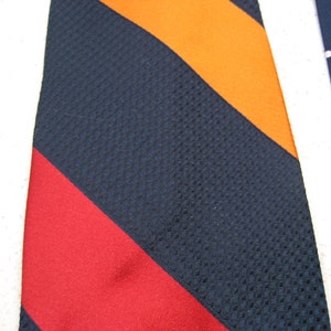 May include: A navy blue tie with orange, red, and white stripes. The tie has a textured pattern.