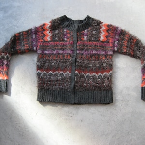 May include: A gray, orange, and pink patterned cardigan sweater with a button closure.