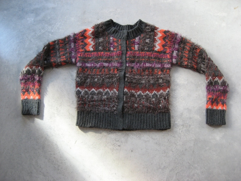 May include: A gray, orange, and pink patterned cardigan sweater with a button closure.