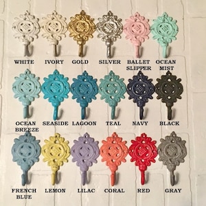 May include: A set of 15 decorative hooks in various colors, including white, ivory, gold, silver, ballet slipper, ocean mist, ocean breeze, seaside, lagoon, teal, navy, black, French blue, lemon, lilac, coral, red, and gray. The hooks are all in the shape of a stylized flower with a hook at the bottom.