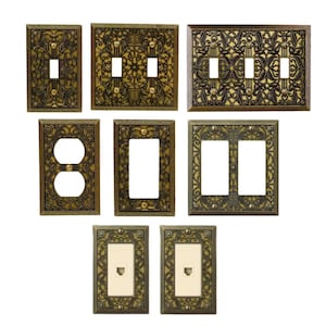 以下が含まれることがあります： さまざまな構成のアンティークスタイルのライトスイッチカバーのコレクション。カバーは、スイッチとコンセント用の切り欠きがあり、金とブロンズの色合いの装飾的でエンボス加工されたデザインが特徴です。コレクションには、シングル、ダブル、コンセントカバーが含まれています。