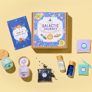 May include: A Galactic Journey Magical Fizzy Potion Kit for ages 4-10. The kit includes a book of spells, jars of Cosmic Dust and Earth Shimmer, and bottles of Stardust Essence. The box is decorated with stars, planets, and a rocket ship.