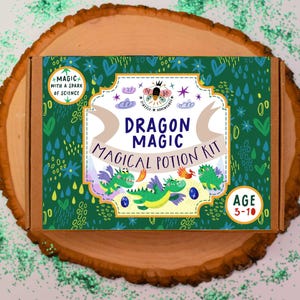 May include: A boxed Dragon Magic Magical Potion Kit, suitable for ages 3-10, is displayed on a wooden slice. The box features a green background with illustrations of dragons and the text "Dragon Magic Magical Potion Kit".