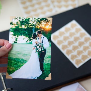 Peut inclure: Une photo de mariage d'un couple s'embrassant dans un champ avec de l'herbe verte et des arbres en arri&egrave;re-plan. La mari&eacute;e porte une robe blanche et le mari&eacute; porte une chemise blanche et un pantalon noir. La photo est encadr&eacute;e d'une bordure en bois.