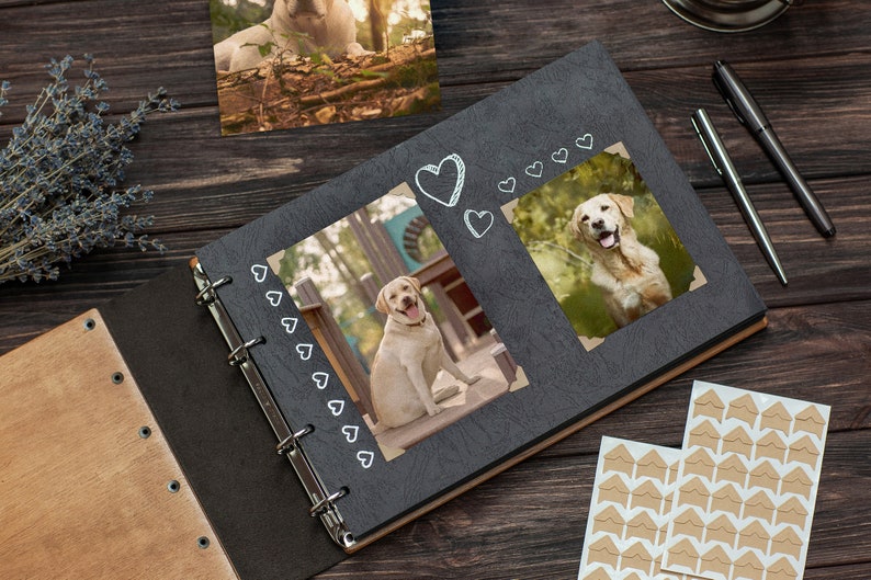 Puede incluir: Un &aacute;lbum de fotos negro con una cubierta de madera y encuadernaci&oacute;n en espiral. El &aacute;lbum tiene dos p&aacute;ginas abiertas, cada una con una foto de un perro golden retriever. El &aacute;lbum tiene un dise&ntilde;o de coraz&oacute;n decorativo en la portada.