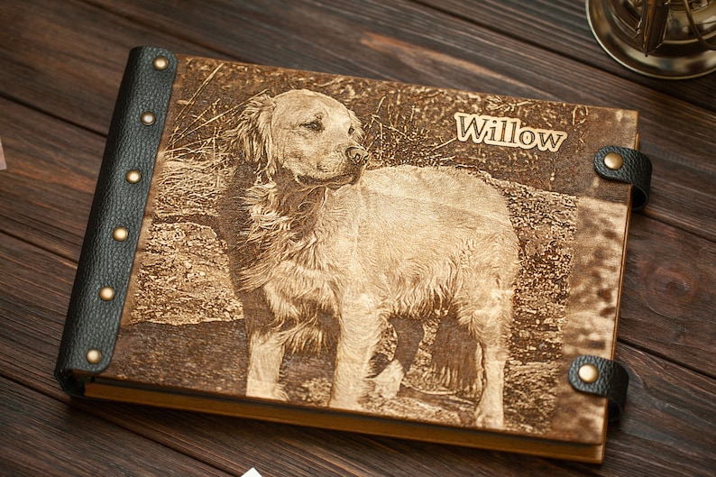 Puede incluir: Un &aacute;lbum de fotos de cuero marr&oacute;n con una imagen grabada con l&aacute;ser de un perro golden retriever. El nombre del perro, "Willow", est&aacute; grabado en la portada.