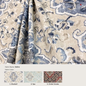 May include: A close-up of a fabric swatch with a blue and beige patterned design. The fabric is called "Sabra" and is available in three colors: Bluebell, Spa, and Cinder Smoke. The fabric is 100% cotton, medium weight, and has a 25-inch vertical repeat.