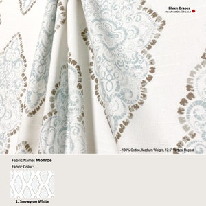 May include: A close-up of a white fabric with a blue and brown paisley pattern. The fabric is 100% cotton, medium weight, and has a 12.5 inch vertical repeat. The fabric is called "Monroe" and the color is "Snowy on White".