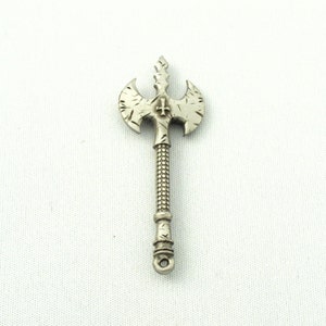 May include: A silver-toned axe pendant with a cross design on the blade. The axe has a detailed, textured surface and a pointed tip.