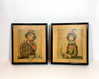 May include: Two framed prints of children with large eyes. The print on the left shows a boy holding a birdcage. The print on the right shows a girl holding a sprig of flowers. Both prints have the text "What a Cute Boy" and "What a Cute Girl" with the artist's name "by Mila" below.