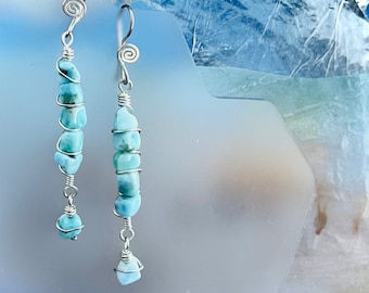 Könnte beinhalten: Handgefertigte Ohrringe mit hellblauen Larimar-Steinen. Die Steine sind mit silberfarbenem Draht in einem Spiraldesign umwickelt. Die Ohrringe haben einen Hakenverschluss.