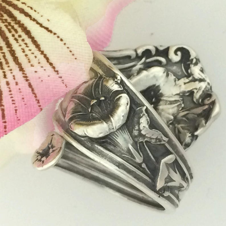 May include: A silver ring made from a vintage spoon with a detailed floral design. The ring features a stylized morning glory flower with leaves.