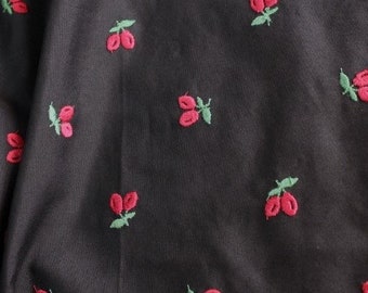 May include: Black fabric with a repeating pattern of red cherries with green stems.