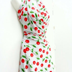 May include: A white halter dress with a cherry print and black polka dots. The dress has a fitted bodice and a flowing skirt.