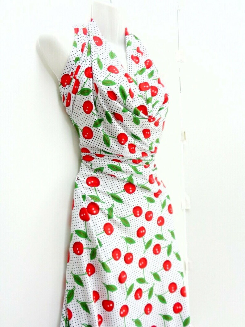 May include: A white halter dress with a cherry print and black polka dots. The dress has a fitted bodice and a flowing skirt.