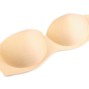 Könnte beinhalten: Ein Paar beigefarbene, trägerlose BH-Einlagen. Die Einlagen bestehen aus einem weichen, glatten Material und haben eine abgerundete Form.
