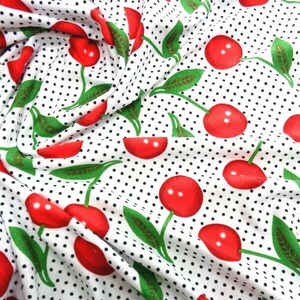 May include: White fabric with a repeating pattern of red cherries and black polka dots.