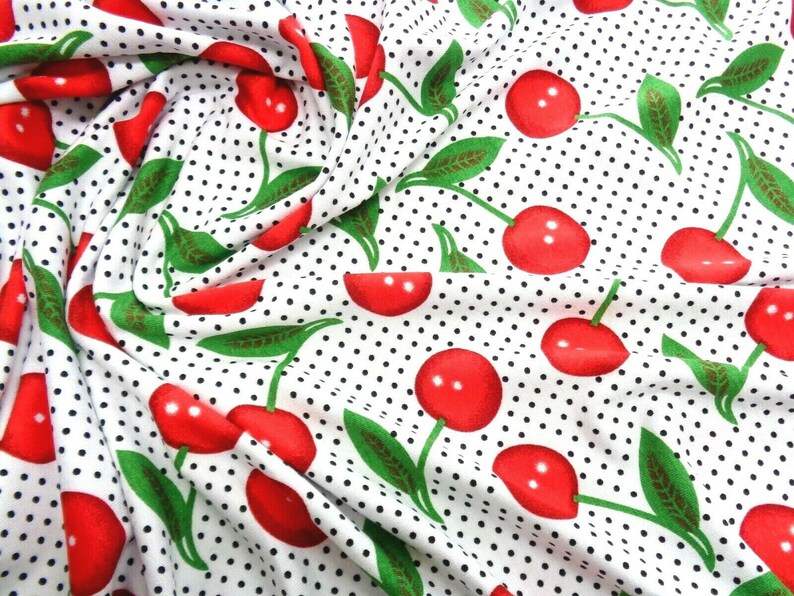 May include: White fabric with a repeating pattern of red cherries and black polka dots.