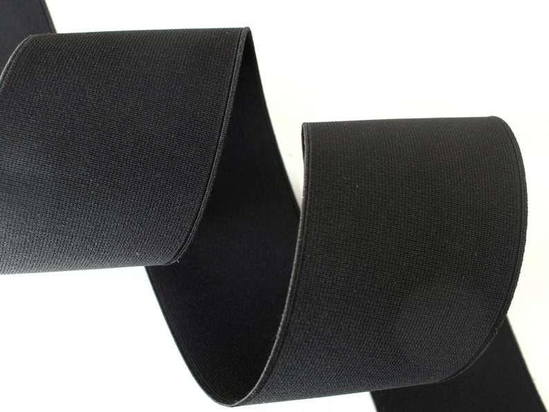 May include: Black elastic band, woven with a textured surface. The band is folded in half, showing the width and texture.