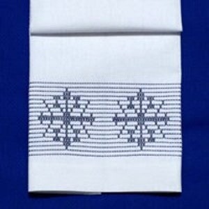 Puede incluir: Toalla de cocina blanca con un diseño de copo de nieve bordado en azul.